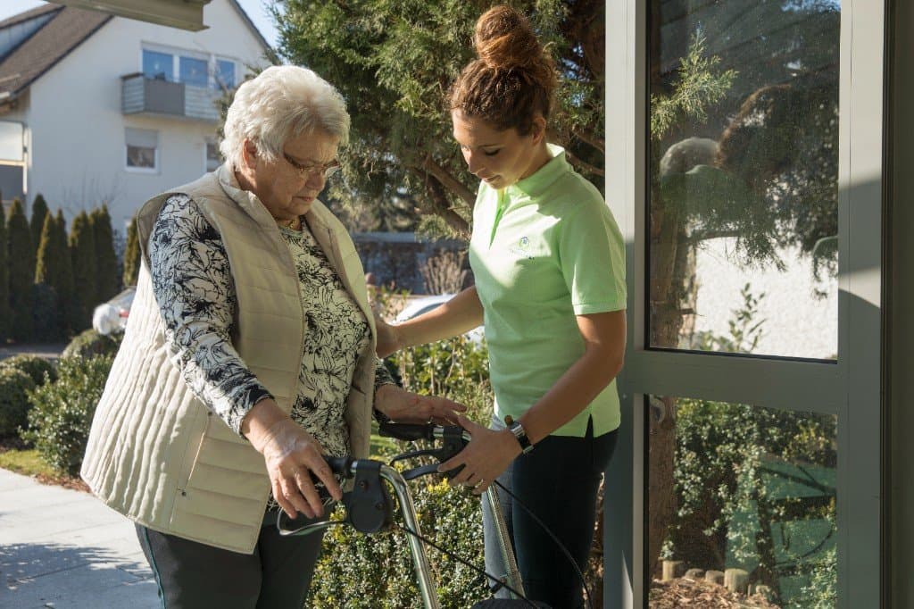 Hilfe im Alltag: Pflegekraft begleitet Seniorin mit dem Rollator